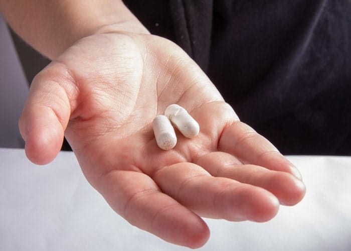 La mano de un hombre sosteniendo dos pastillas.